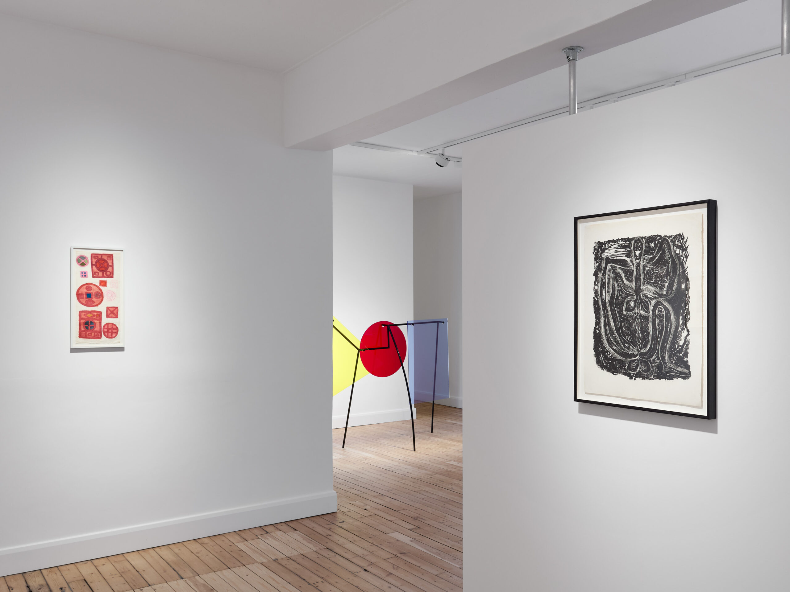 Installation view: Assembly Lines, ANTESALA, London, October 2026. Pictured, left to right: works by Mira Schendel (Mandala series, red and blue watercolor on rice paper, framed), Amalia Pica (coloured Plexiglass geometric elements mounted on a black-painted steel armature), and Maria Martins (black and white framed lithograph of a snake-like, vegetal creature). Photo: Ollie Hammick.